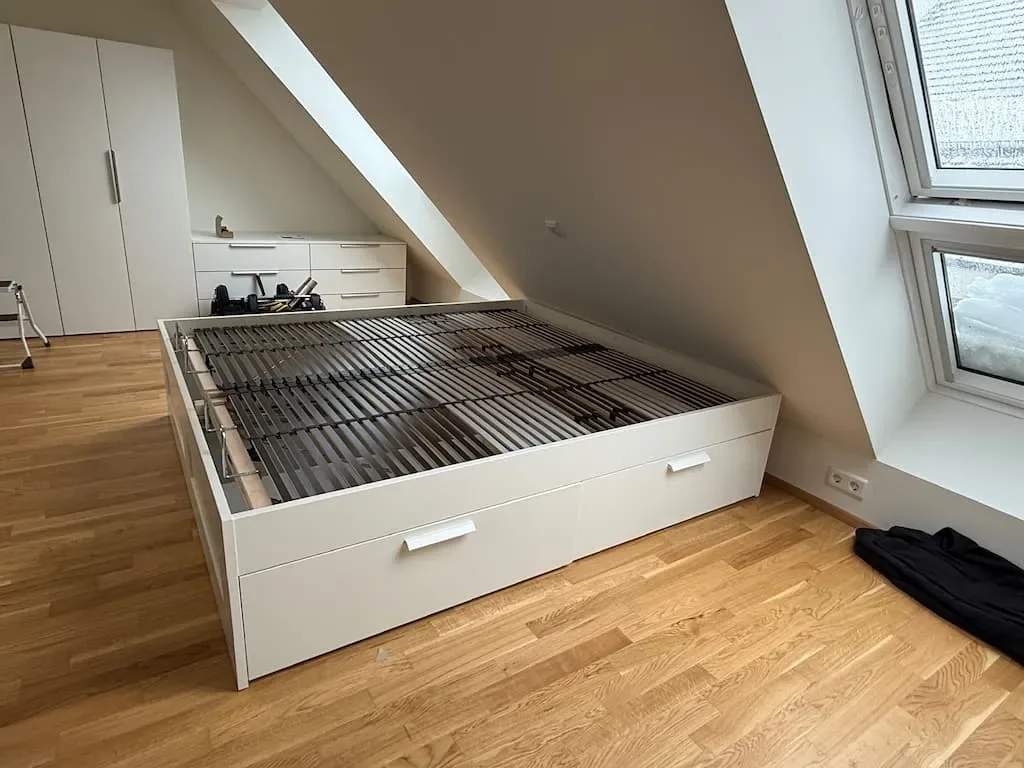 Weißes Bett mit Schubladen unter einer Dachschräge