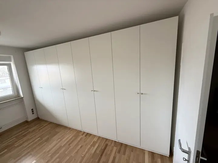 Großer weißer Kleiderschrank mit Drehtüren.