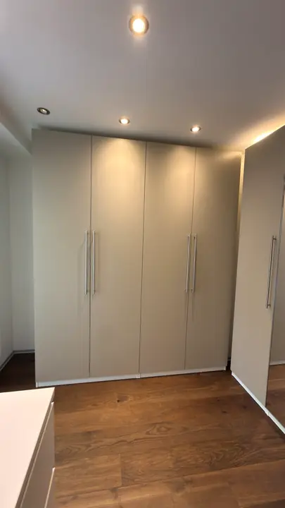 Grauer Kleiderschrank mit Drehtüren.