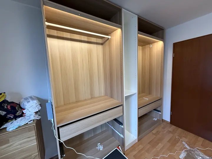 Kleiderschrank während der Montage mit Schubladenauszügen und integrierter LED-Beleuchtung.