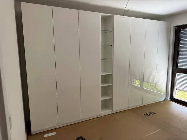 Weißer PAX Kleiderschrank mit glänzenden Fronten.