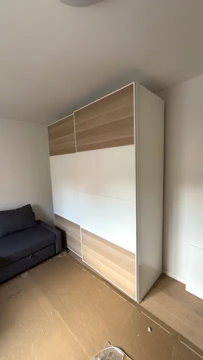 Montierter Kleiderschrank mit Schiebetüren in Holzoptik und Weiß.