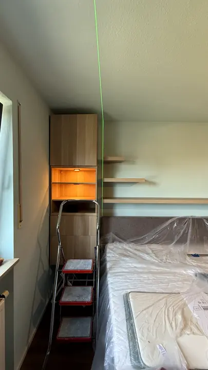 Präzise Ausrichtung von Wandregalen mit Laser während der Montage im Schlafzimmer.