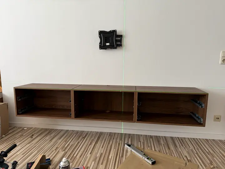Ausrichtung eines wandhängenden TV-Lowboards mit Kreuzlinienlaser und Montage des TV-Halters.